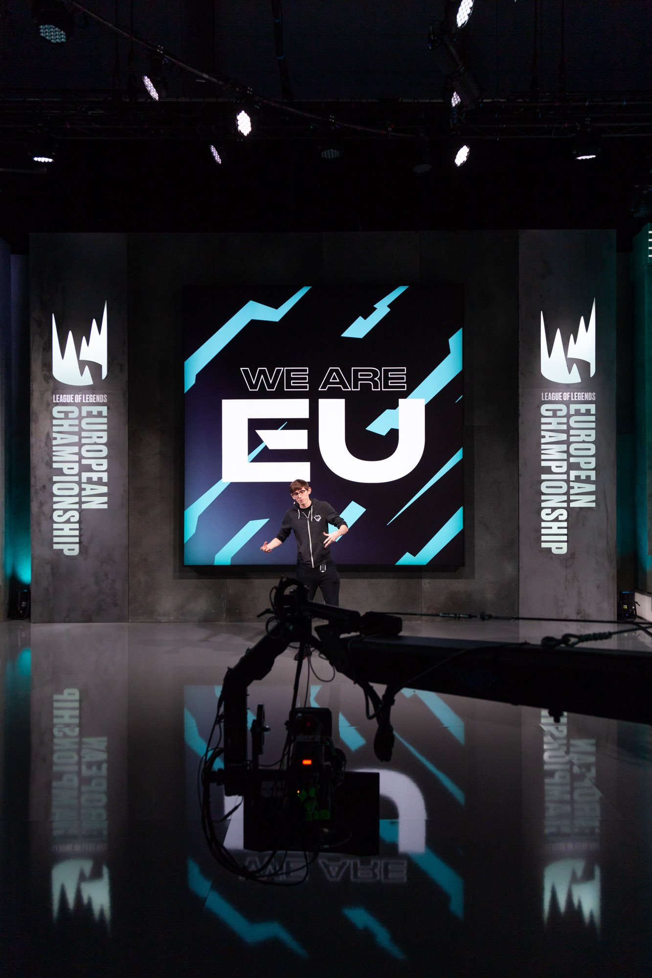 Moderator stark gestikulierend vor dem WE ARE EU Logo mit Kamerakran im Anschnitt